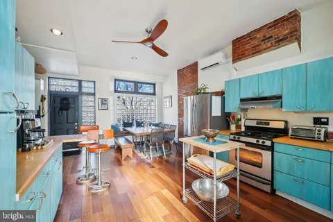 a kitchen with stainless steel appliances kitchen island granite countertop a stove top oven a sink a dining table and chairs with wooden floor