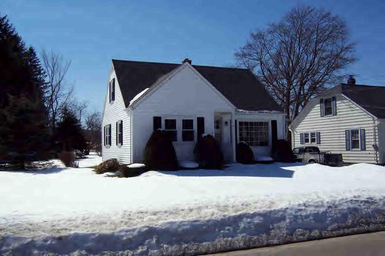 a front view of a house with a yard covered in snow