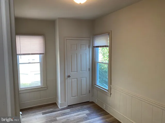 an empty room with wooden floor closet and windows