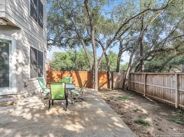 a view of a backyard with table and chairs and a large tree