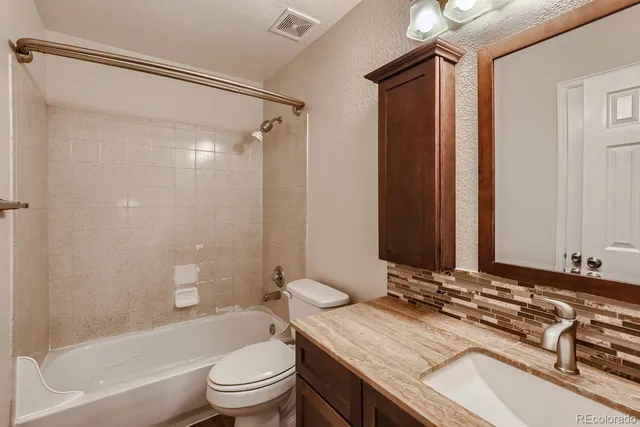 a bathroom with a granite countertop sink toilet and shower