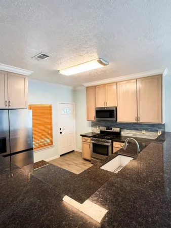 a kitchen with stainless steel appliances granite countertop a stove a sink and a refrigerator