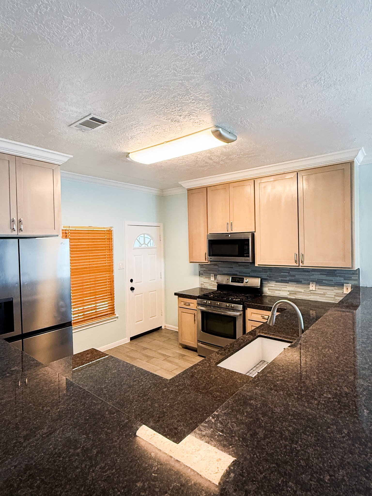 3348 Reeves Street Houston, TX 77004 - Photo 12 of 14 a kitchen with stainless steel appliances granite countertop a stove a sink and a refrigerator