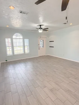 an empty room with windows and ceiling fan