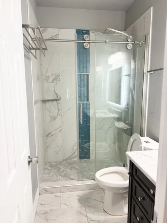 a bathroom with a granite countertop toilet a sink and shower