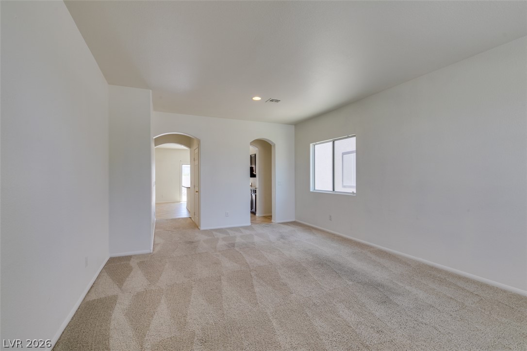 5150 Riverside Run Court North Las Vegas, NV 89081 - Photo 3 of 50 A spacious room featuring comfortable carpeting and multiple arched doorways leading to other areas of the home.