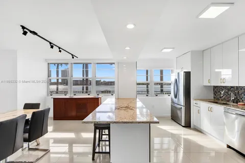 a kitchen with stainless steel appliances kitchen island granite countertop a refrigerator and a stove top oven