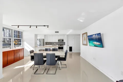 a view of a dining room with furniture a kitchen and chandelier