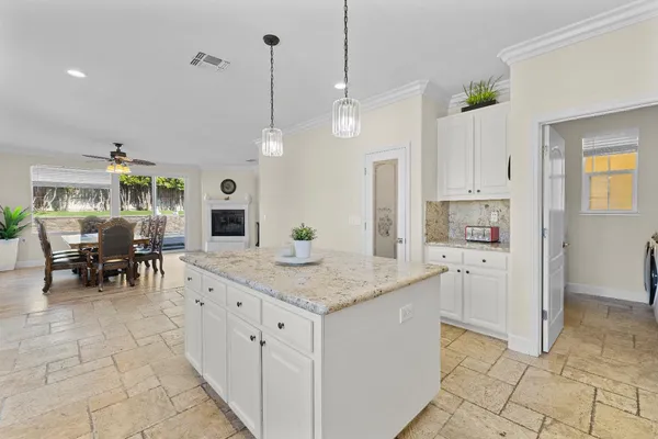 a kitchen with stainless steel appliances kitchen island granite countertop a table chairs and a refrigerator