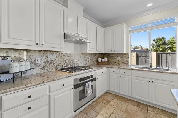 a kitchen with granite countertop white cabinets and white appliances
