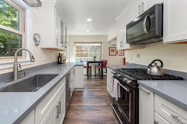 a kitchen with stainless steel appliances granite countertop a sink stove top oven and cabinets