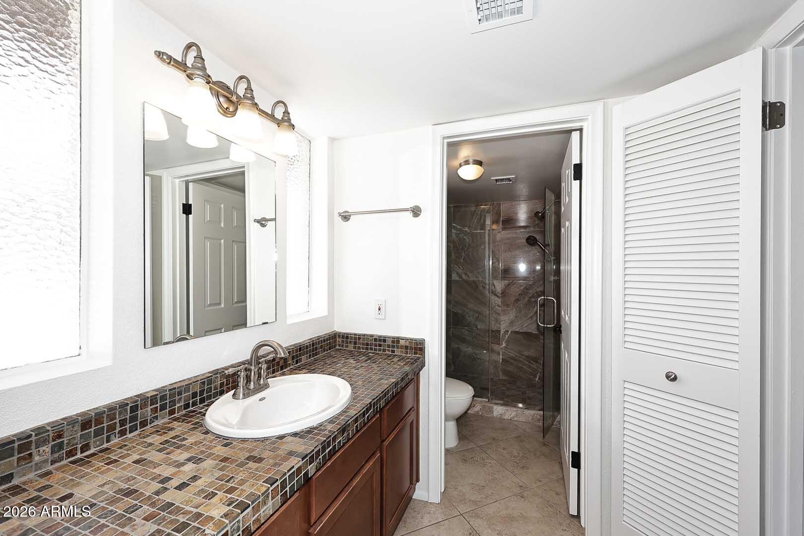 5426 South Lighthouse Lane Tempe, AZ 85283 - Photo 33 of 60 a bathroom with a granite countertop sink toilet a mirror and shower