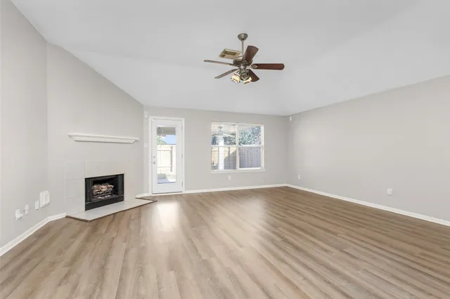 a view of empty room with wooden floor and fireplace