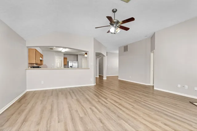 a view of a livingroom with a ceiling fan wooden floor and a ceiling fan