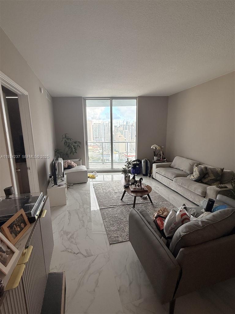 185 Southwest 7th Street, Unit 3109 Miami, FL 33130 - Photo 5 of 25 a living room with furniture a window and gym equipment