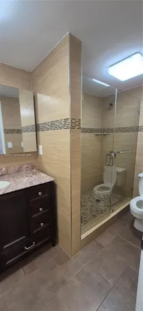a bathroom with a granite countertop sink a toilet and shower
