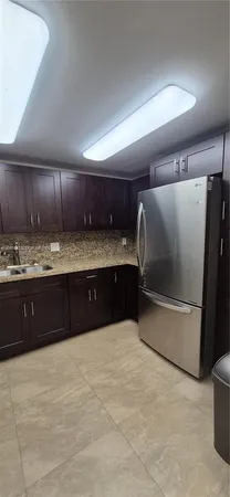 a kitchen with granite countertop a refrigerator and a sink