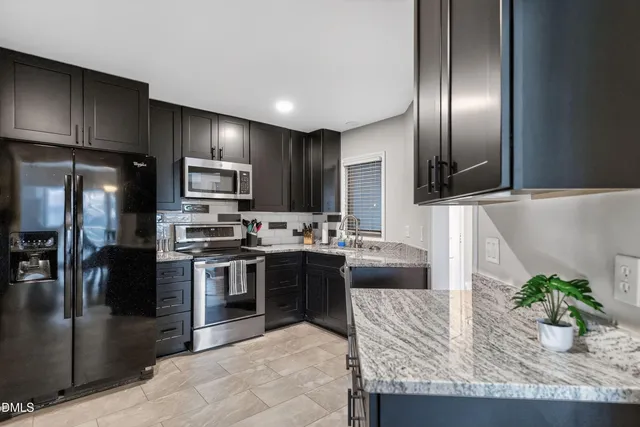 a kitchen with stainless steel appliances granite countertop a stove a sink and a refrigerator