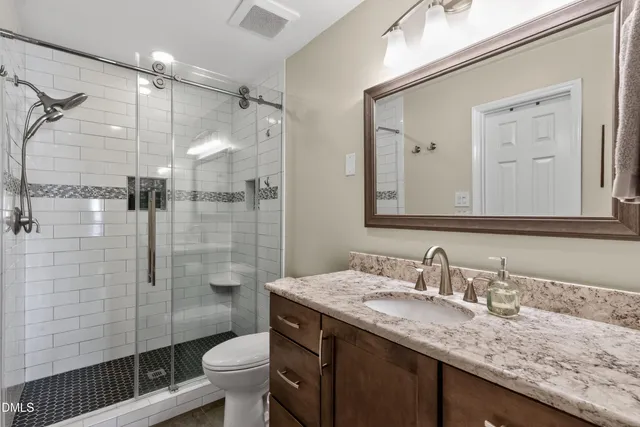 a bathroom with a granite countertop sink toilet and shower