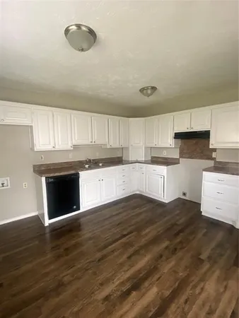 a large kitchen with cabinets wooden floor and stainless steel appliances