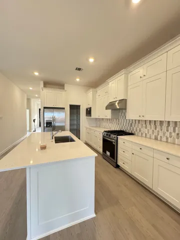 a kitchen with stainless steel appliances kitchen island granite countertop a stove top oven a sink with granite countertops and cabinets