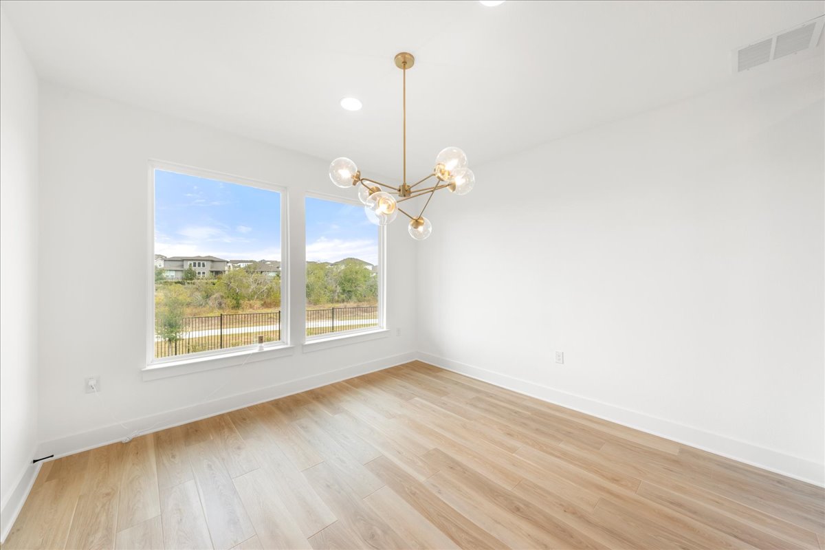 8700 Olmsted Way Austin, TX 78744 - Photo 13 of 40 Empty room with light wood finished floors, a chandelier, and recessed lighting