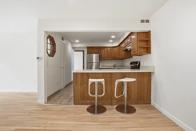 a room with stainless steel appliances kitchen island granite countertop a stove and a refrigerator
