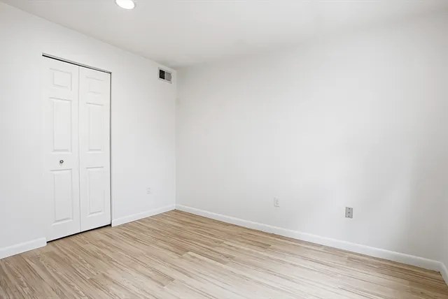 a view of an empty room with wooden floor and closet