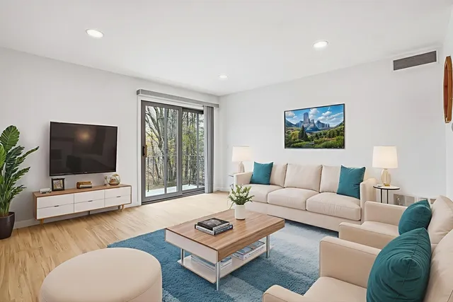 a living room with furniture a flat screen tv and a window