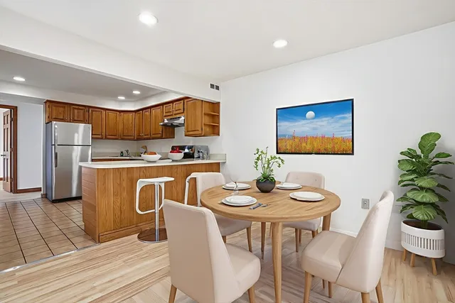 a dining room with furniture a wooden floor and a kitchen view