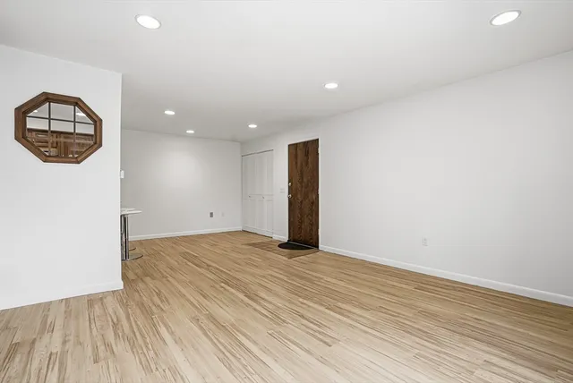 an empty room with wooden floor and window