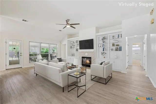 a living room with furniture a fireplace a flat screen tv and a large window