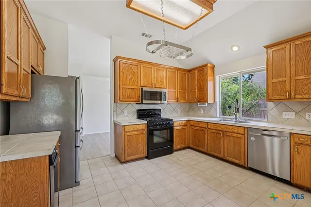 a kitchen with stainless steel appliances granite countertop a stove top oven a sink dishwasher and a refrigerator