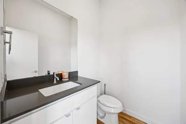 a bathroom with a granite countertop sink and a toilet