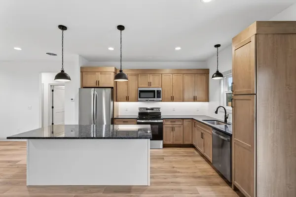 a kitchen with stainless steel appliances granite countertop a sink a stove and a refrigerator