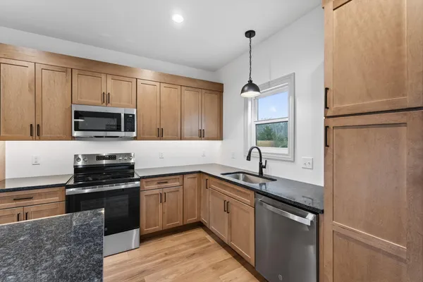 a kitchen with stainless steel appliances granite countertop a sink a stove and a wooden floors