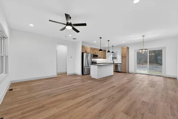 a view of empty room with wooden floor and fan