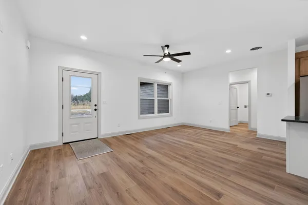 a view of an empty room with a window and wooden floor