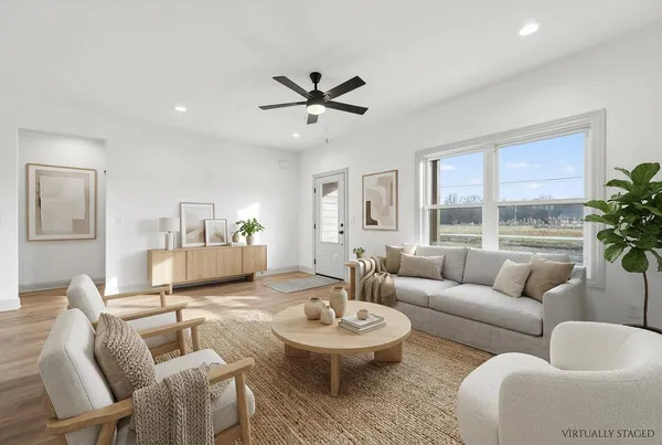 a living room with furniture kitchen view and a wooden floor