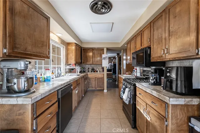 a kitchen with stainless steel appliances granite countertop a stove top oven a sink dishwasher and a refrigerator with the cabinets