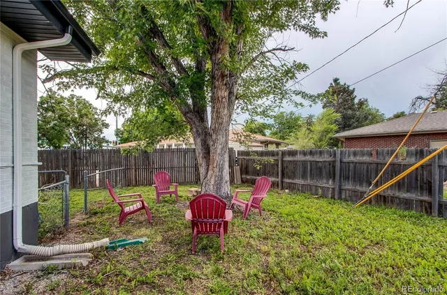 a view of a backyard with a slide trees and wooden fence