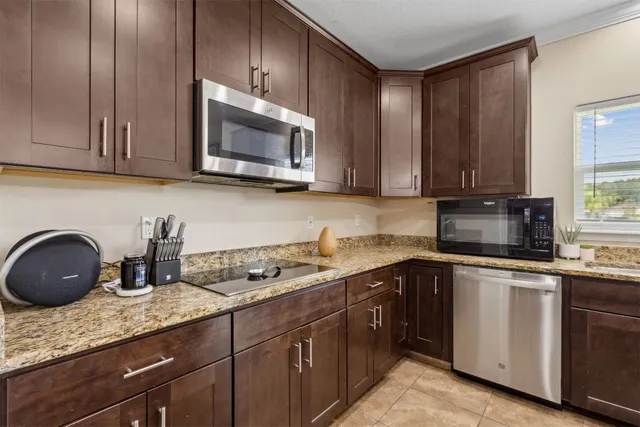 a kitchen with granite countertop stainless steel appliances a sink counter space and living room view