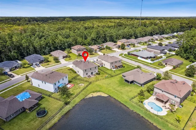 an aerial view of a house with swimming pool and large trees