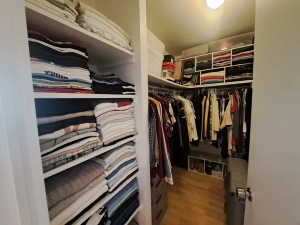 a view of walk in closet with clothes and shoes