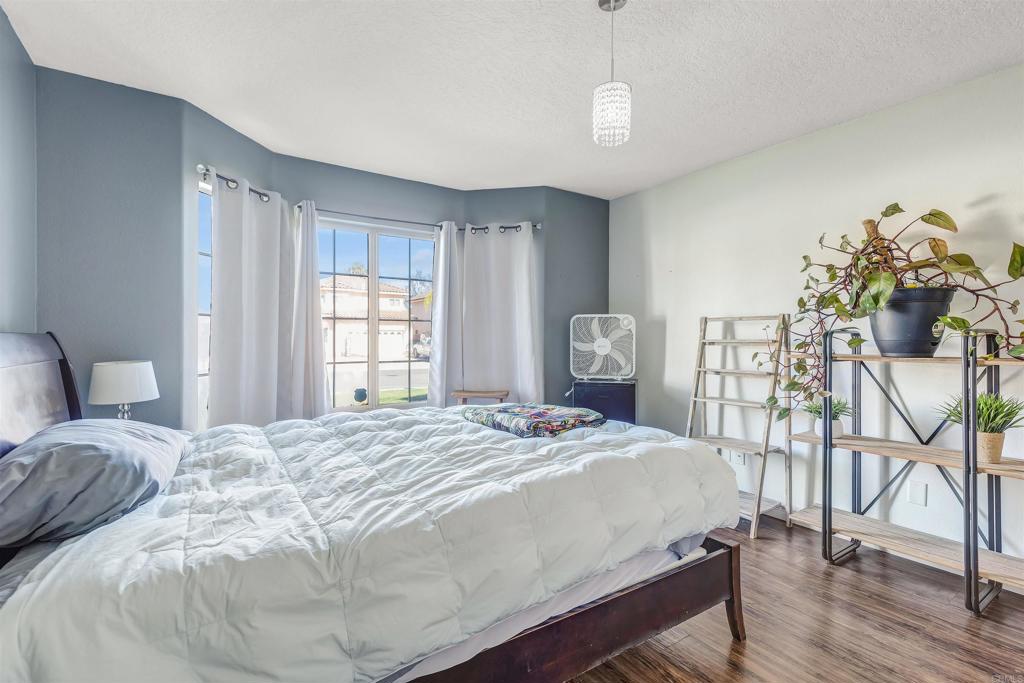 4559 Coronado Drive Oceanside, CA 92057 - Photo 20 of 29 a bedroom with a bed a table and potted plants with wooden floor
