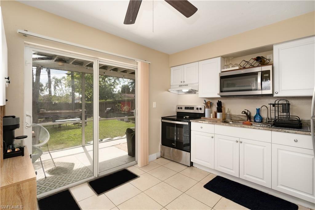 11580 Dean Street, Unit 582 Bonita Springs, FL 34135 - Photo 5 of 22 Kitchen featuring appliances with stainless steel finishes, under cabinet range hood, a sink, a ceiling fan, and white cabinets