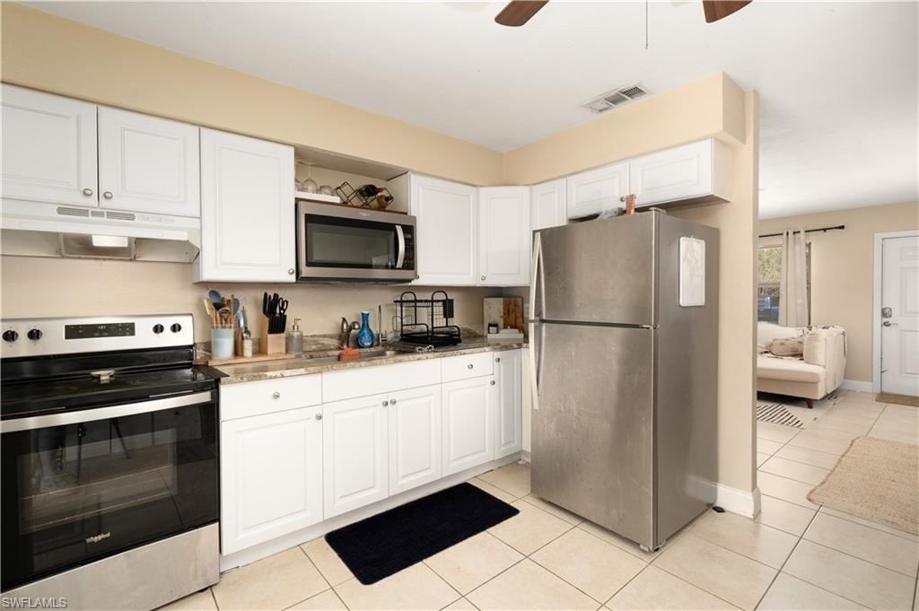 11580 Dean Street, Unit 582 Bonita Springs, FL 34135 - Photo 6 of 22 Kitchen with appliances with stainless steel finishes, under cabinet range hood, white cabinets, light tile patterned floors, and a ceiling fan