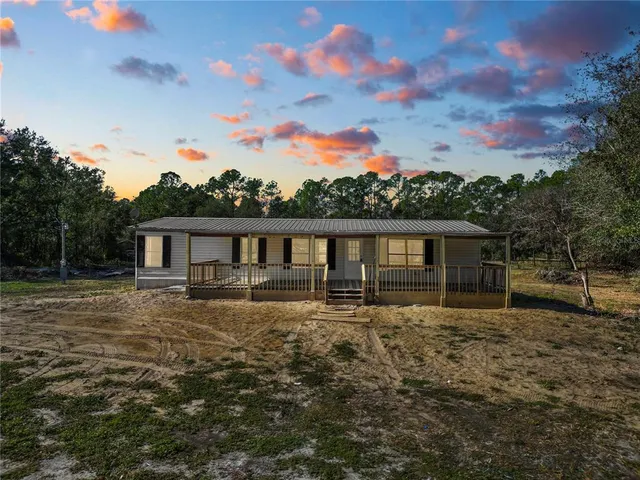 a front view of house with yard and trees in the background