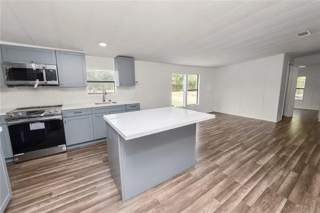 a kitchen with stainless steel appliances a sink a stove a refrigerator and cabinets