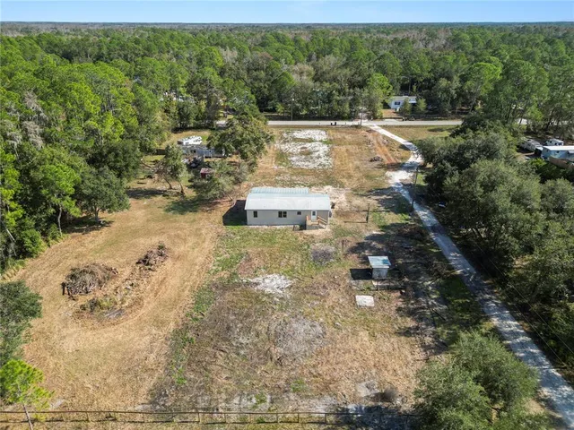 an aerial view of residential houses with outdoor space and trees